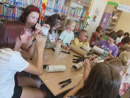 Dzieci na kolorowych tubach malują różne wzory swoich domków.