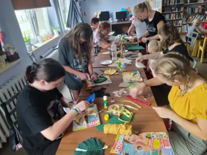 Uczestniczki wycinają sznurki, wyczesują oraz przyklejają listki do tekturki.