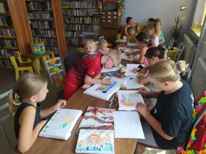 Dzieci malują kredkami obrazy na kartkach.