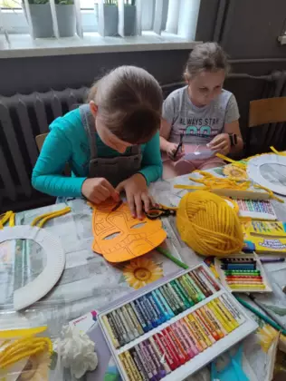 Dziewczyny kolorują maski z papieru.