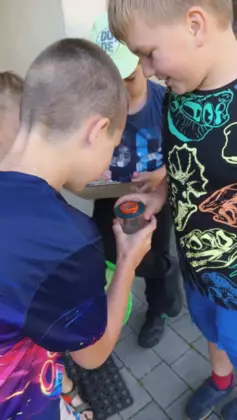 Chłopcy obserwują lupą owady zamknięte w słoiku.