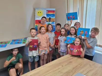 Wspólne zdjęcie po zajęciach plastycznych. Dzieci trzymają w rękach prace plastyczne przedstawiające lody.