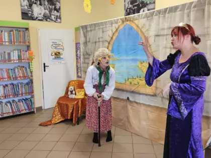 Aktorki przebrane za postacie bajkowe - księżniczkę i babcię - przedstawiają spektakl w bibliotece.