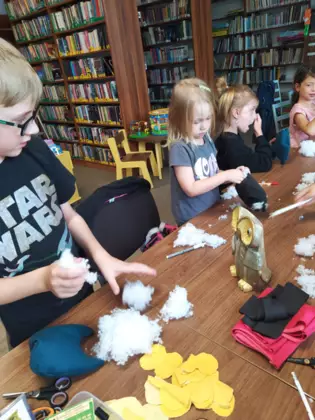 Dzieci szyją sówki i wypełniają je watą.