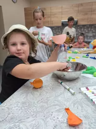 Dziewczynka wsypuje do butelki suchy produkt aby następnie wsypać go do balonika.
