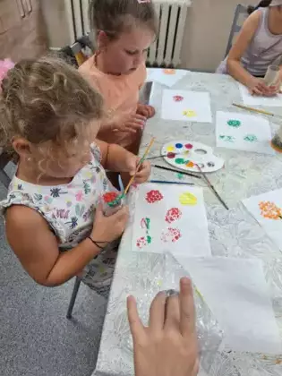 Dziewczynki folią bąbelkową malują obrazki na ręczniku papierowym.