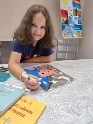 Dziewczynka maluje obrazek kotka na folii aluminiowej.