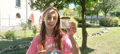 Dziewczyna trzyma w ręce pojemnik w którym ma mrówkę.