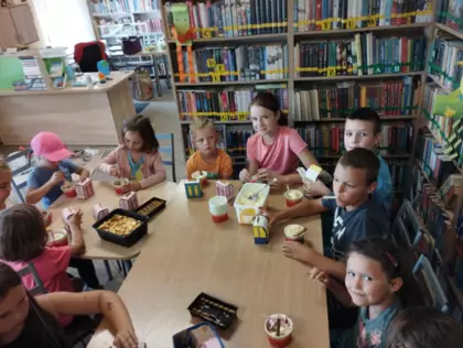 Uczestnicy siedzą przy stoliku i częstują się ciasteczkami.