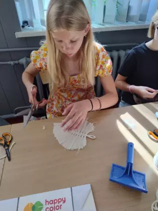 Dziewczyna wycina z makramy listek.