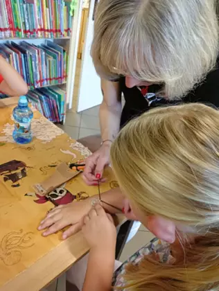 Dziewczynki wykonują bransoletki na rękę.