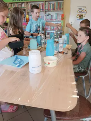 Uczestnicy sznurkiem oklejają słoiki.