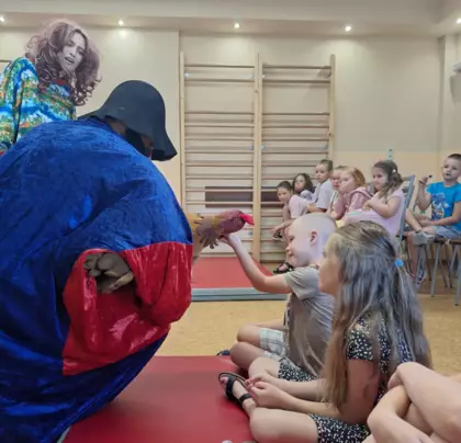 Aktor daje dzieciom do pogłaskania kurę znoszącą złote jajka.