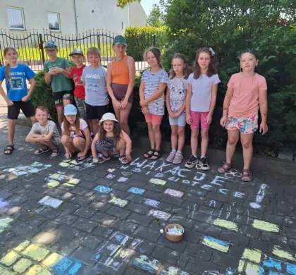 Wspólne zdjęcie na tle rysunków pomalowanych kreda na chodniku.