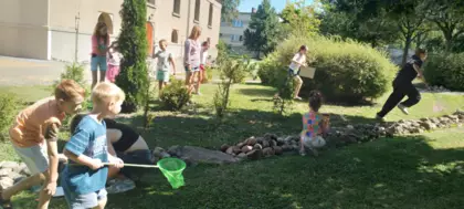 Dzieci biegają po trawie łapiąc motyle do siatki.