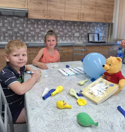 Chłopczyk i dziewczynka malują mazakami baloniki.