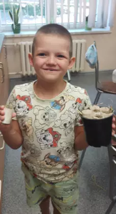Chłopczyk trzyma w rękach doniczkę zrobioną na zajęciach.