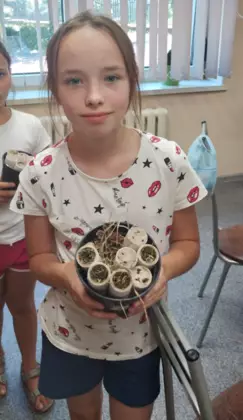 Dziewczynka trzyma w rękach doniczkę zrobioną na zajęciach.