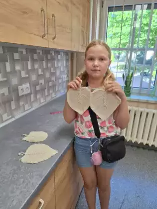 Dziewczyna pokazuje swoje listki, które wykonała na zajęciach.