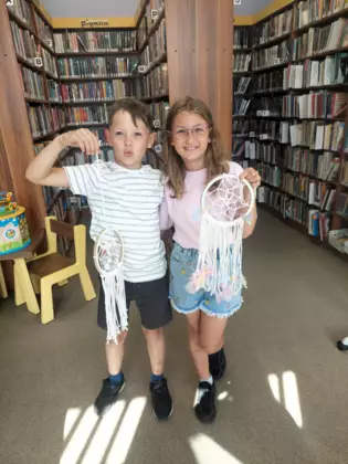 Chłopiec i dziewczynka przedstawiają swoje makramowe lapacze snów.