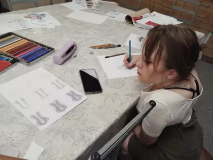 Uczestniczka szkicuje ołówkiem części twarzy.