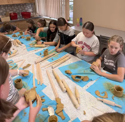 Warsztaty ceramiczne. Dzieci z gliny wykonują kubki.