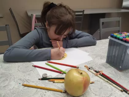 Dziewczyna rysuje i cieniuje jabłko.