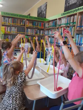 Dzieci podnoszą ręce do góry rozciągając slima.