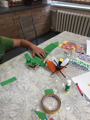 Na stole papierowy zielony krokodyl i pszczoła. 