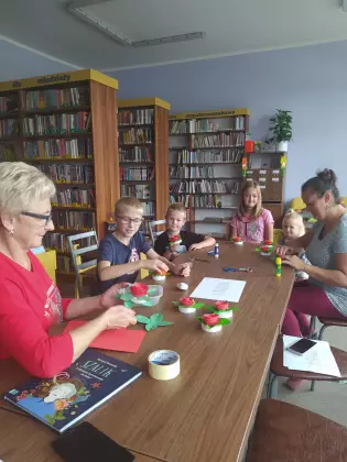 Uczestnicy kleją z papieru kwiaty dla Wisławy Szymborskiej.