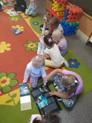 Przedszkolaki oglądają książki przyniesione z biblioteki.