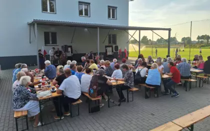 Uczestnicy koncertu biesiadujący przy stołach.