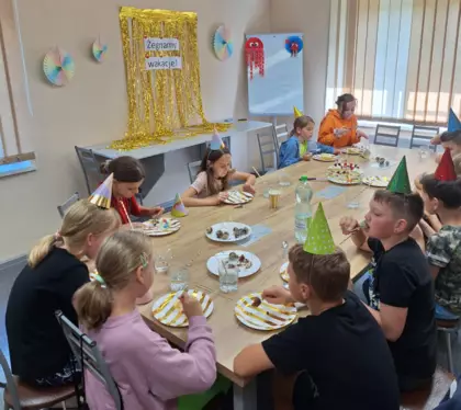 Dzieci częstują się tortem i lizakami.