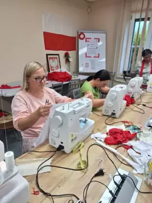 Uczestniczki zajęć szyją na maszynie koszulki.