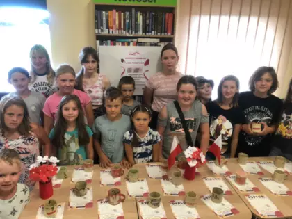 Dzieci pozują do wspólnego zdjęcia z kubkami i dyplomami.