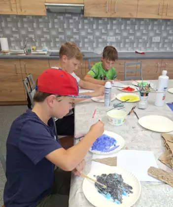 Chłopcy malują farbami obrazek.