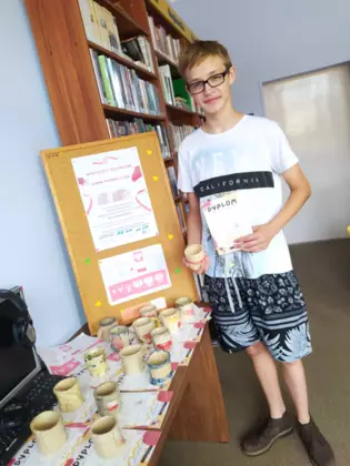 Chłopak odbiera swój kubek ceramiczny i dyplom.