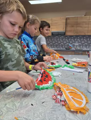 Chłopcy wypełniają owocowe piniaty cukierkami.