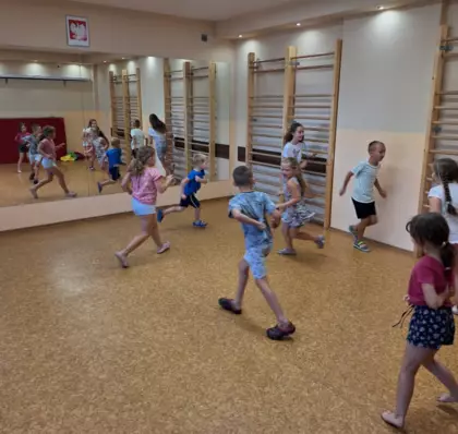 Dzieci biegają po sali gimnastycznej.