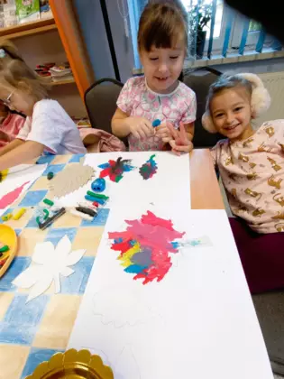 Dwie dziewczynki w trakcie tworzenia swoich kolorowych liści.