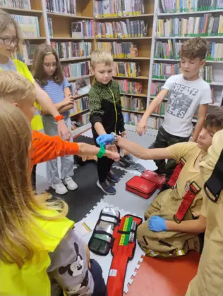 Dzieci przyklejają kolorowe opaski na rękach.