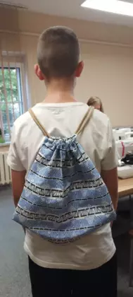 Uczestnik pokazuje na plecach swój uszyty workoplecak.