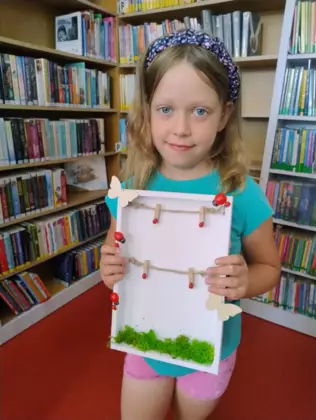 Dziewczynka z pomalowaną ramką na zdjęcia.