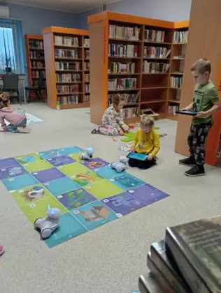 Dzieci w bibliotece na tabletach programują przejście dla robotów.