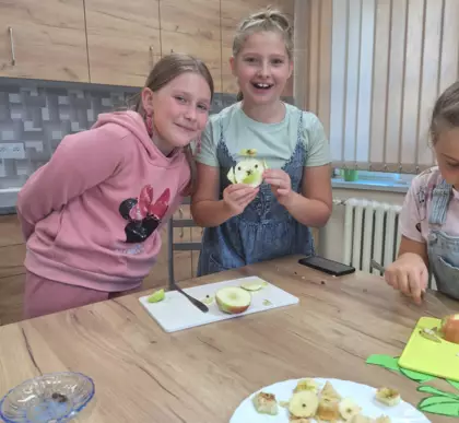 Dwie dziewczynki pokazują wykonana sówkę z jabłka.