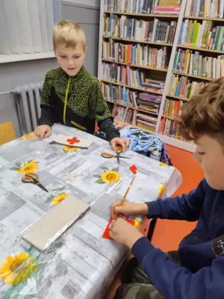 Chłopcy wycinają z kolorowego papieru opaski na włosy.