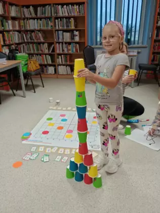 Dziewczynka z kolorowych kubków ułożyła wysoką wieżę.