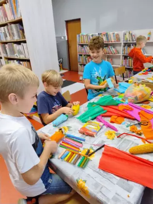 Chłopcy przy stoliku z kukurydzy tworzą ludziki.