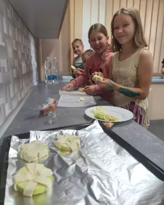 Dzieci z jabłek i ciasta francuskiego pieką przepyszne przysmaki.