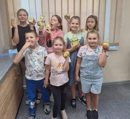 Wspólne zdjęcie dzieci po zajęciach trzymające w rękach owocowe stworki.